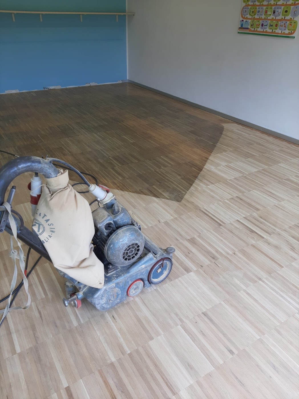 Levigatrice professionale durante la rigenerazione di un vecchio pavimento in legno