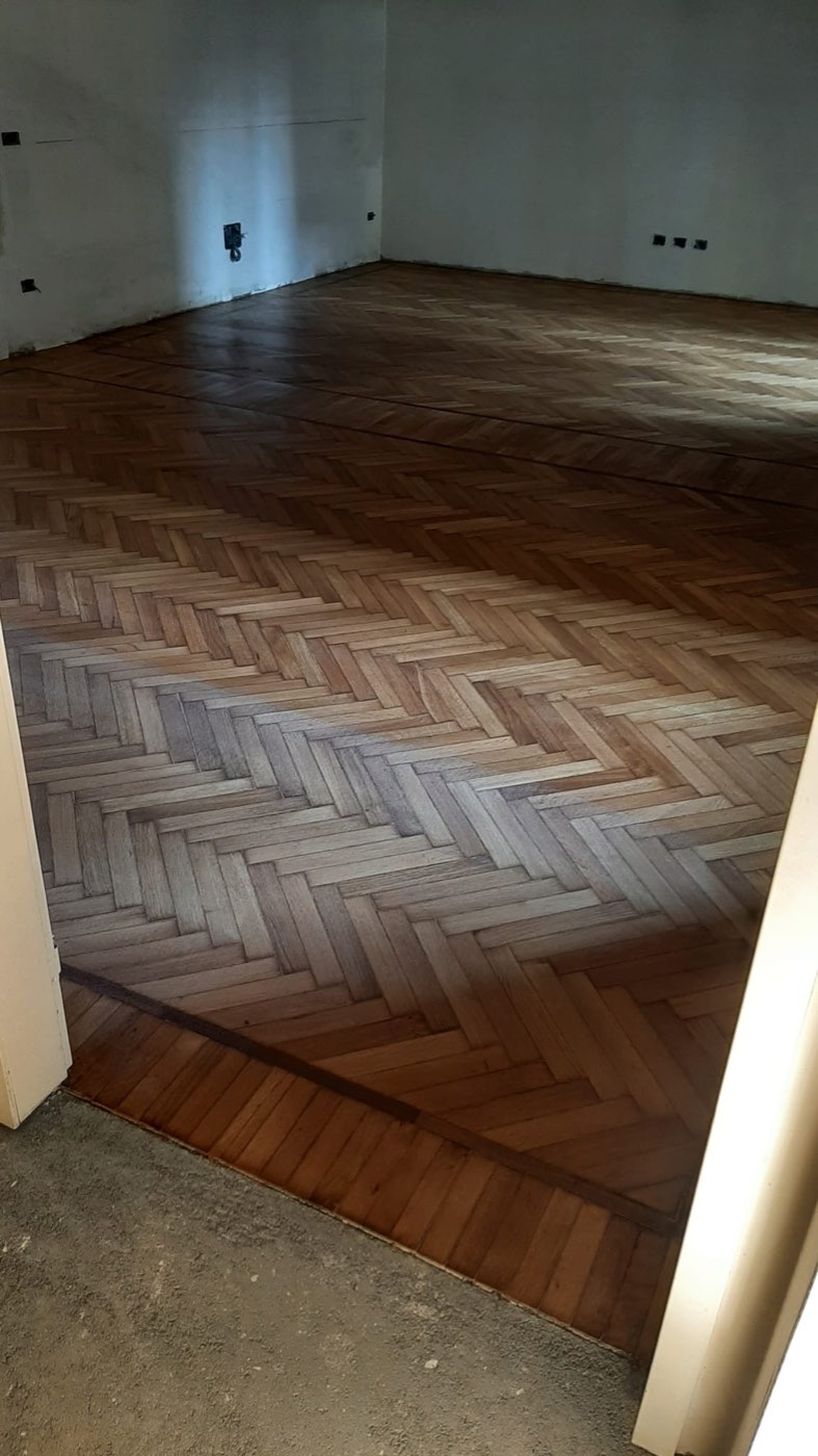 Pavimento a spina di pesce con bordo perimetrale bicolore visto dalla soglia di una porta